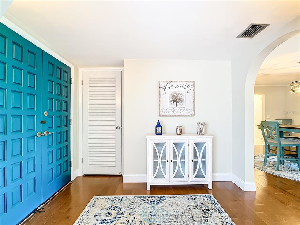 An entryway features a teal door, a white louvered closet, and a white storage cabinet — 2250 WATROUS DR, DUNEDIN, FL
