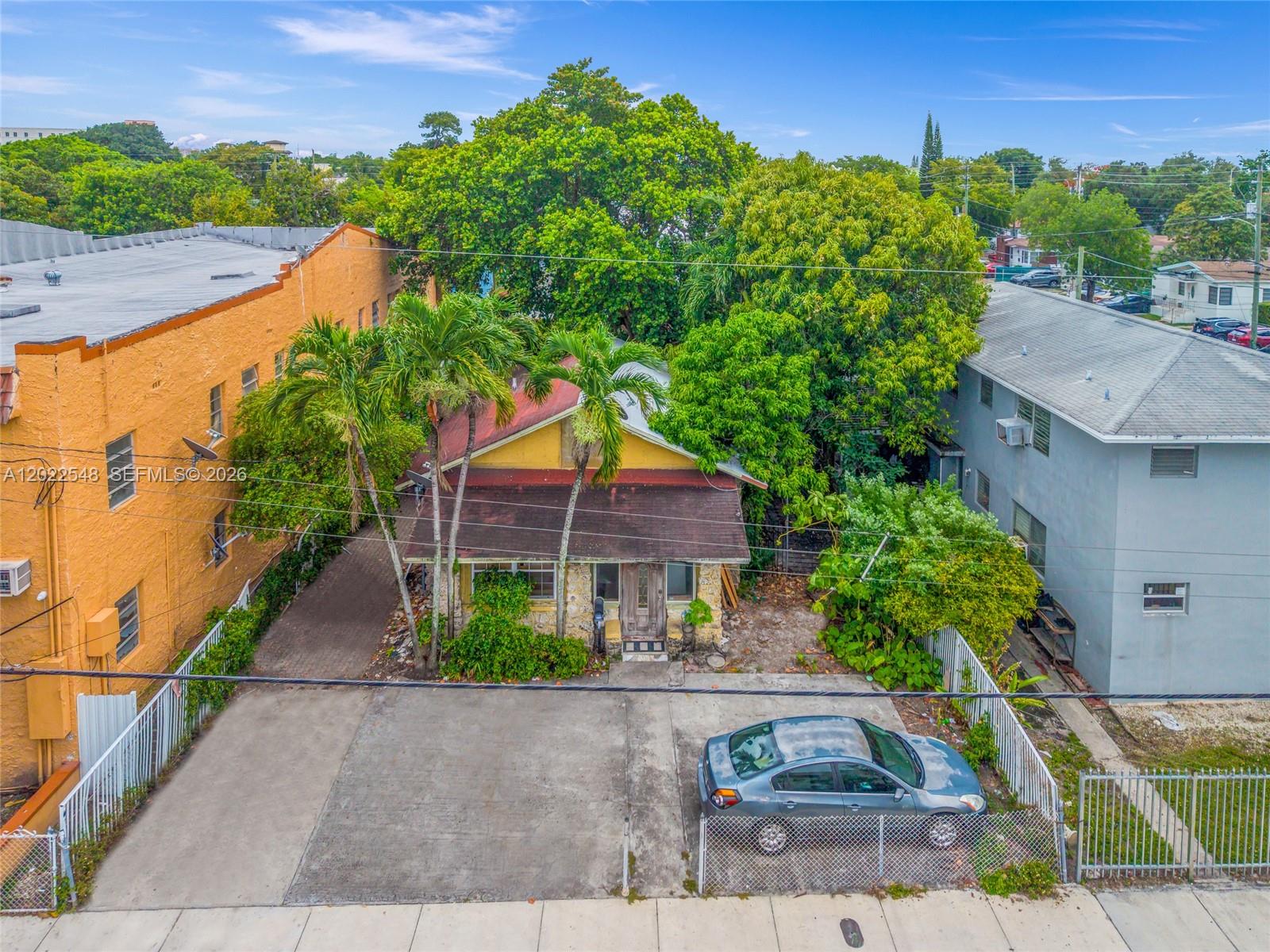 An aerial view shows a small yellow house nestled between two larger buildings — 1568 SW 5th St, Miami FL 33135, MIAMI, FL