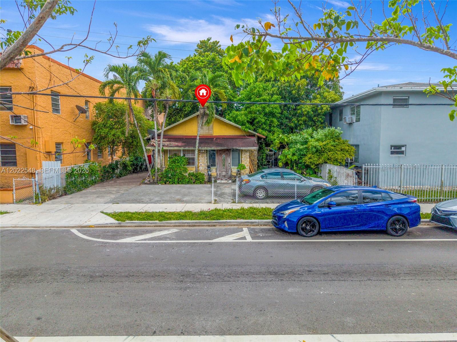 A yellow single-story house sits between two larger buildings with cars parked in front — 1568 SW 5th St, Miami FL 33135, MIAMI, FL