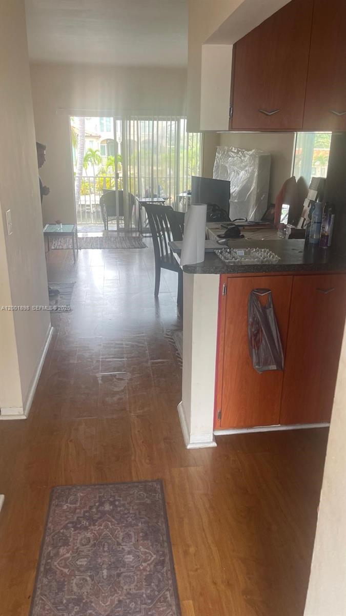 A kitchen with wood cabinets and a counter overlooks a living area with tile floors — 2225 NE 123rd St # 204, North Miami FL 33181, NORTH MIAMI, FL