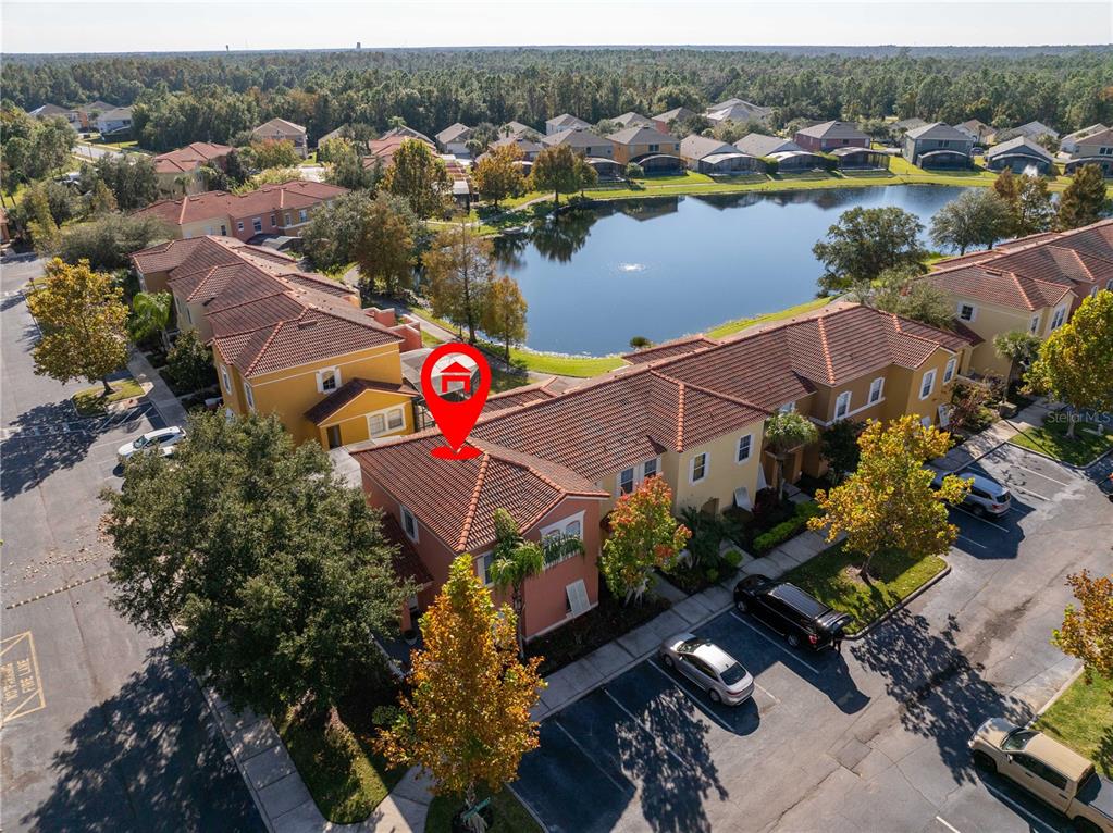 An aerial view shows a multi-story residential building with a red tile roof near a lake — 4722 FLAGLER BEACH WAY, KISSIMMEE, FL