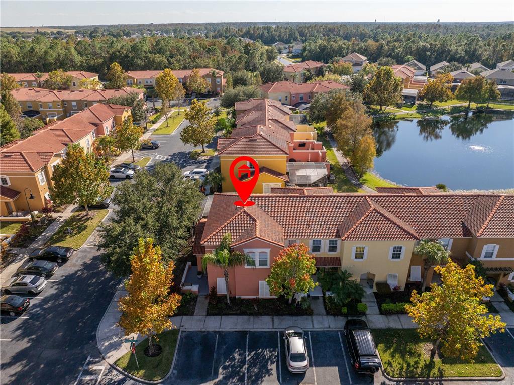 An aerial view shows a multi-story townhouse complex with tile roofs and a nearby pond — 4722 FLAGLER BEACH WAY, KISSIMMEE, FL