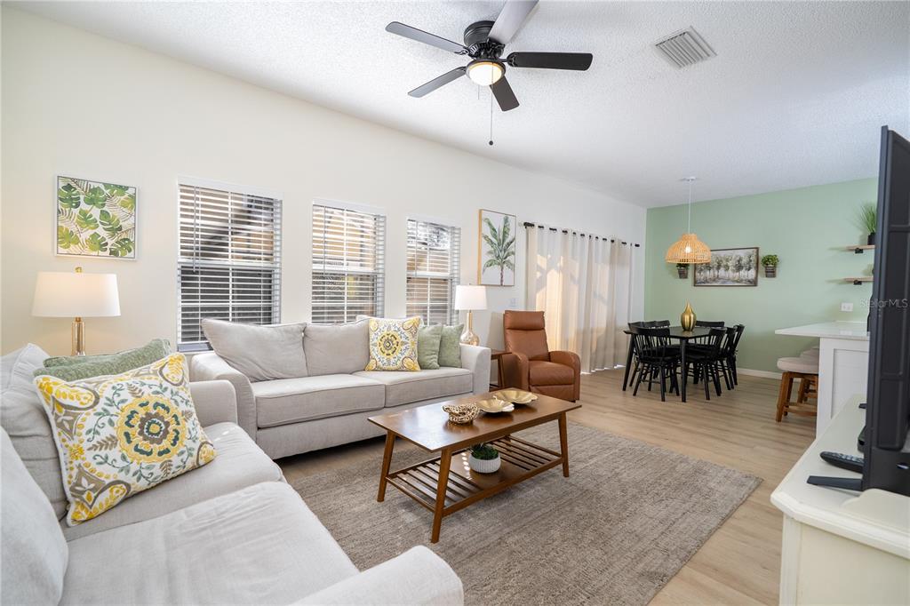 A living room with a light gray sofa, wooden coffee table, and adjacent dining area — 4722 FLAGLER BEACH WAY, KISSIMMEE, FL