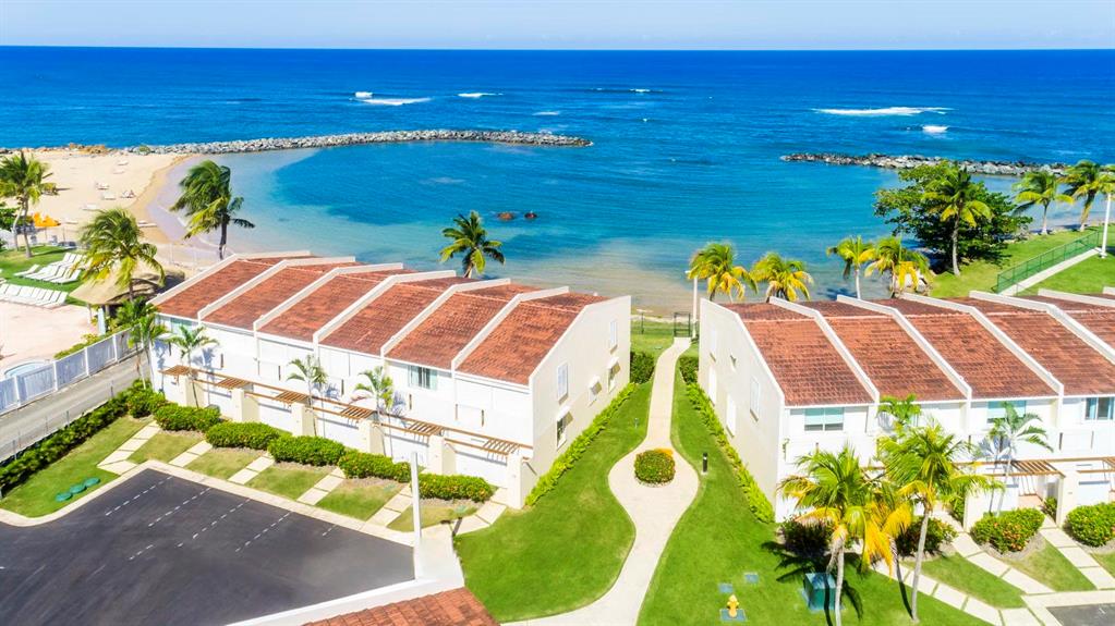 An aerial view shows two rows of townhouses with terracotta roofs near a sandy beach — Dorado del Mar Blvd OCEAN VILLAS UNIT 39, DORADO, PR