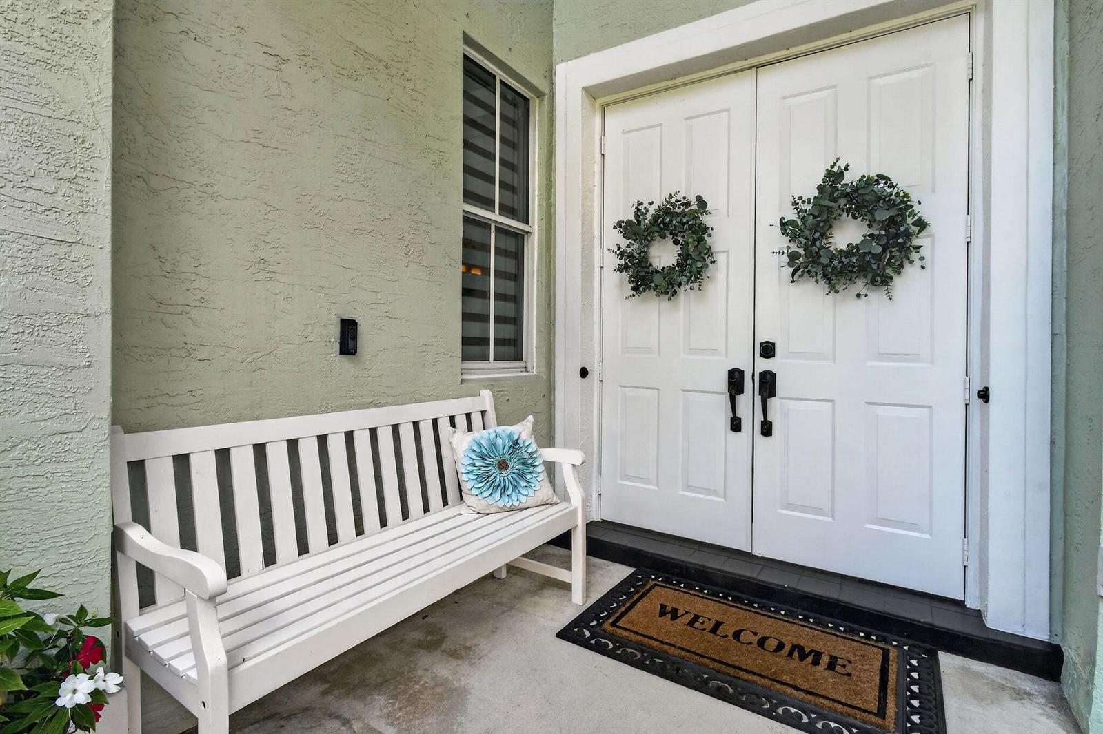 A white bench sits on a porch next to double doors with wreaths — 265 Swallowtail Lane, Jupiter FL 33458, JUPITER, FL