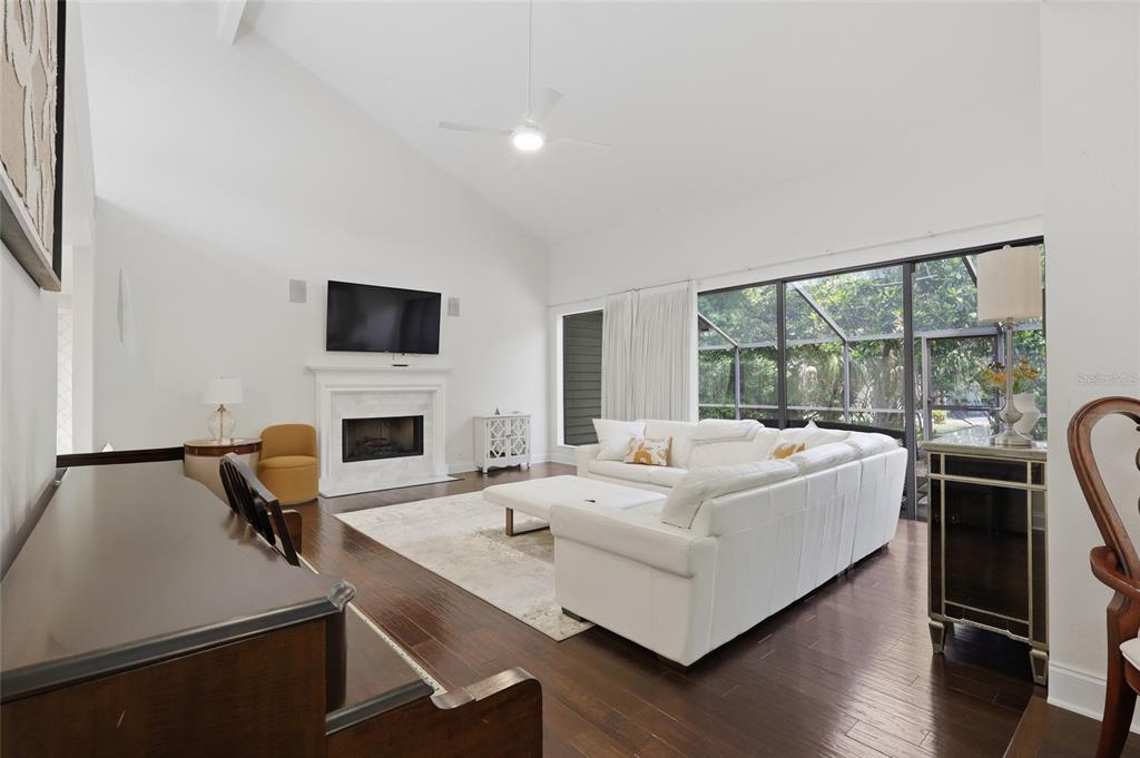 A living room features a vaulted ceiling, fireplace, white sectional sofa, and dark wood floors — 5344 COBBLESTONE COURT, WESLEY CHAPEL, FL