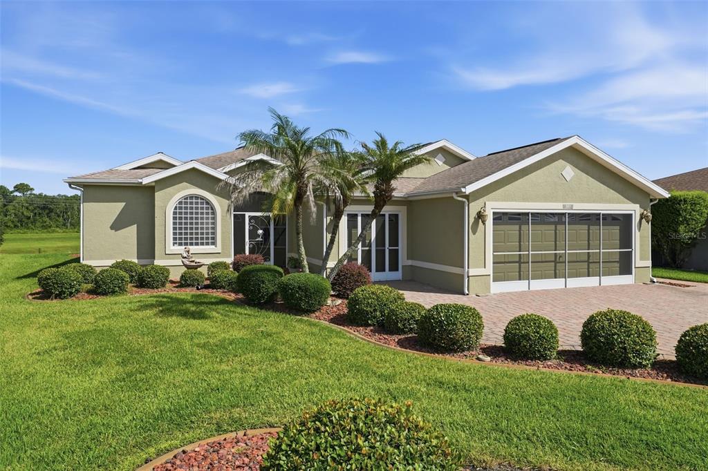 A single-story house with a green exterior, a paved driveway, and a manicured lawn — 307 GRAND VISTA TRAIL, LEESBURG, FL