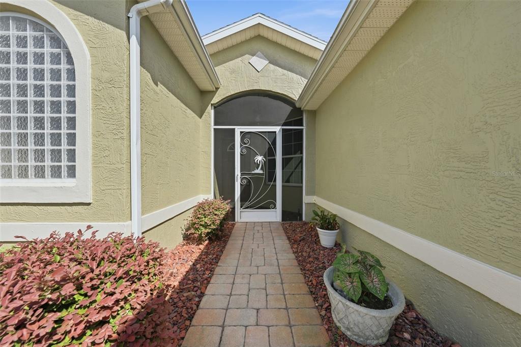 A paved walkway leads to a front entrance with a decorative screen door — 307 GRAND VISTA TRAIL, LEESBURG, FL