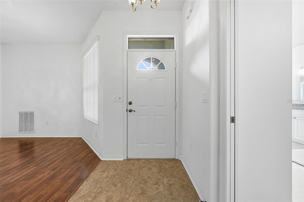 An entryway features a white front door, tile flooring, and adjacent wood-look flooring — 307 GRAND VISTA TRAIL, LEESBURG, FL