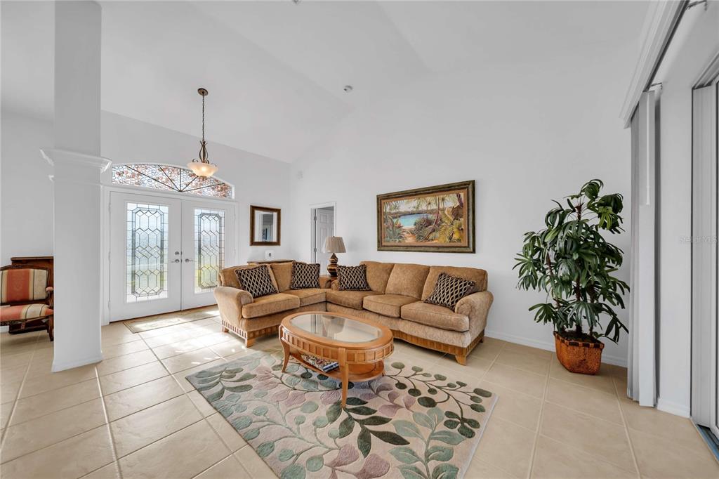 A living room features a tan sectional sofa, a glass-topped coffee table, and tile flooring — 240 WHITE MARSH LANE, ROTONDA WEST, FL