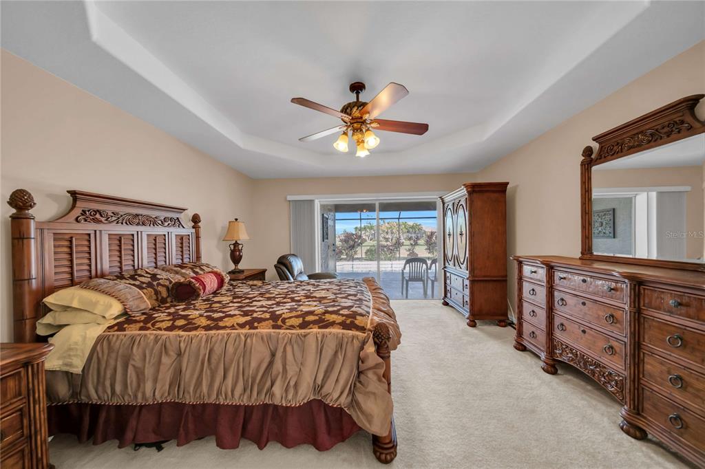 A bedroom features a wooden bed frame, matching dresser with mirror, armoire, and sliding glass doors — 240 WHITE MARSH LANE, ROTONDA WEST, FL