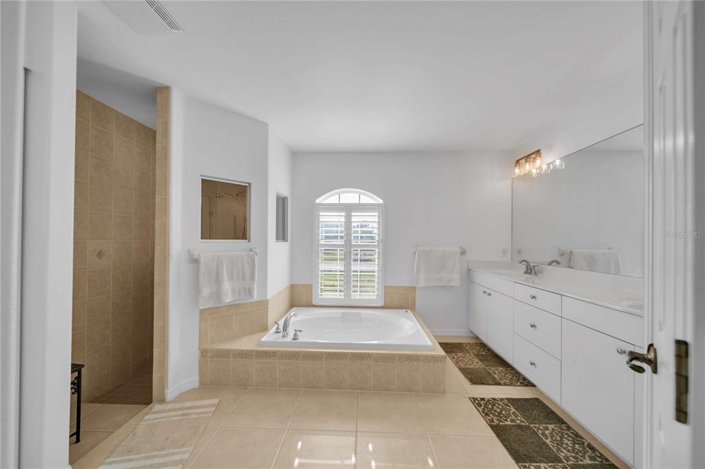 A primary bathroom features a soaking tub, a double vanity, and a walk-in shower — 240 WHITE MARSH LANE, ROTONDA WEST, FL