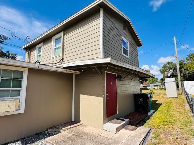 A two-story house with tan siding features a red door and a small concrete patio — 2722 S SUNRISE COURT UNIT C, ORLANDO, FL