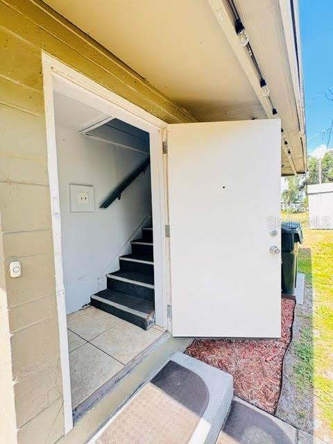 An open white door reveals an interior staircase with dark steps and tiled flooring — 2722 S SUNRISE COURT UNIT C, ORLANDO, FL