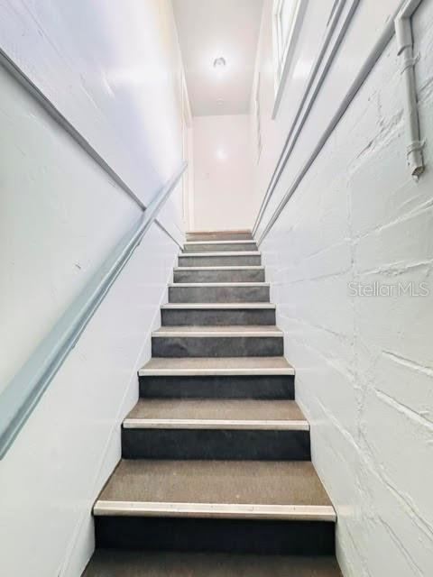A straight staircase with dark carpeted treads leads upward between white painted walls — 2722 S SUNRISE COURT UNIT C, ORLANDO, FL