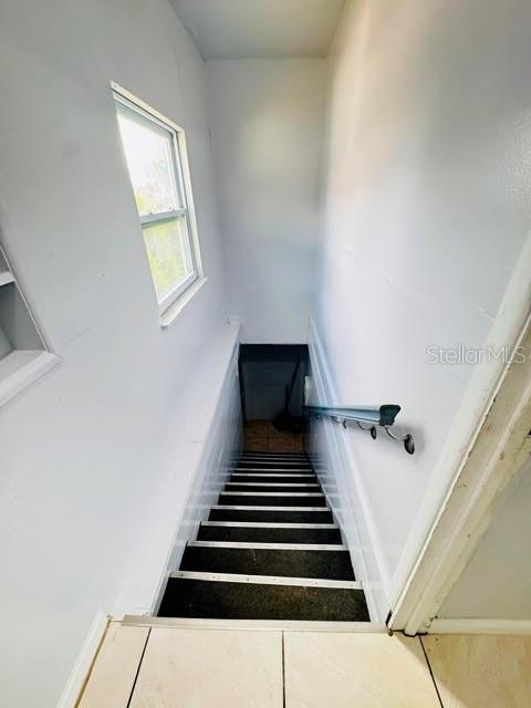 A narrow staircase with dark treads and a metal handrail leads down to a basement — 2722 S SUNRISE COURT UNIT C, ORLANDO, FL