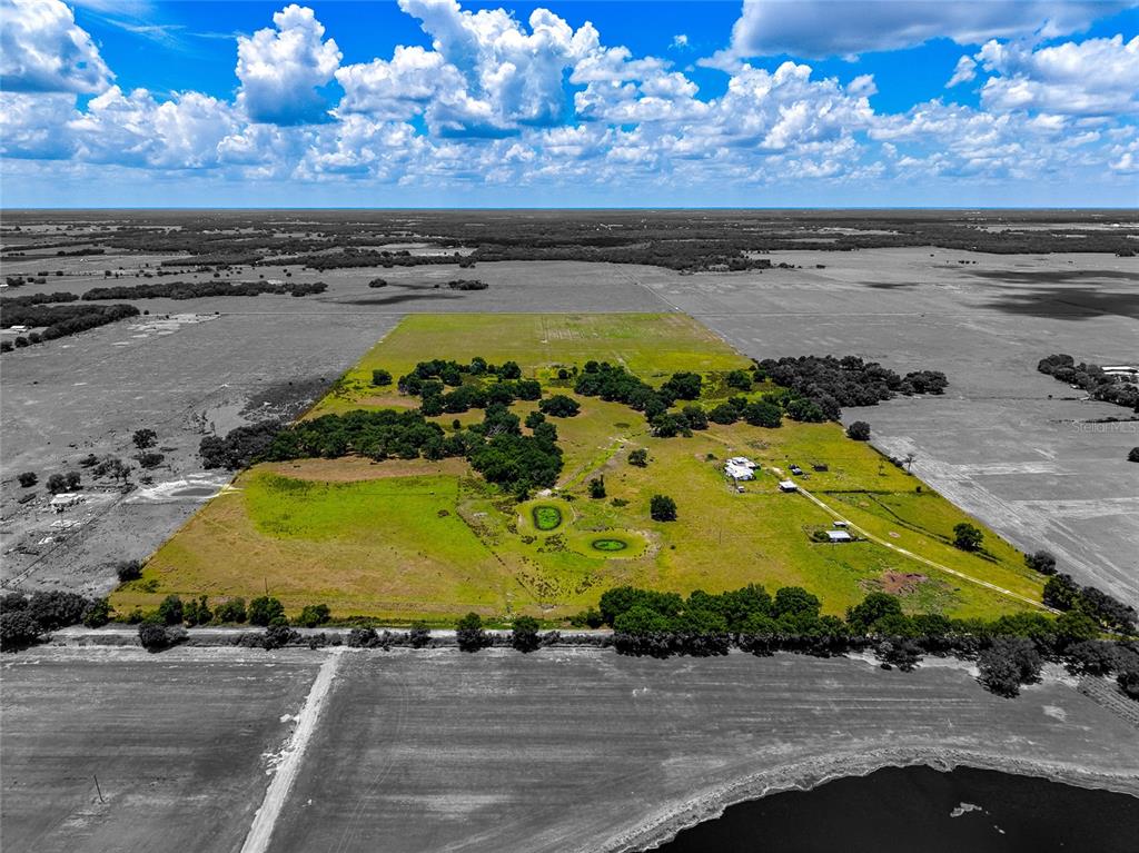An aerial view shows a large, grassy rural property with scattered trees and several buildings — 3030 N NURSERY ROAD, ZOLFO SPRINGS, FL
