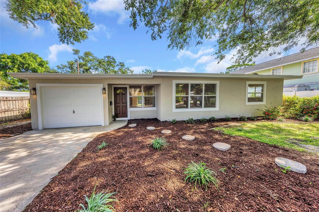 A single-story house with a garage, brown front door, and a mulched front yard — 8017 31ST AVENUE N, ST PETERSBURG, FL