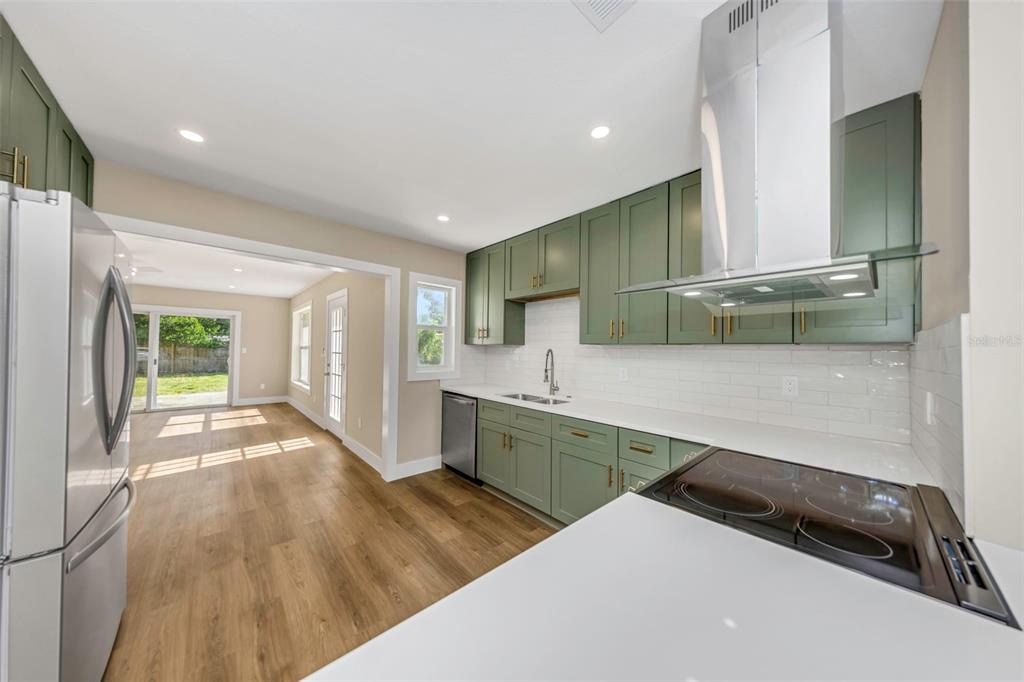 A kitchen with green cabinets, white countertops, stainless steel appliances, and wood-look flooring — 8017 31ST AVENUE N, ST PETERSBURG, FL