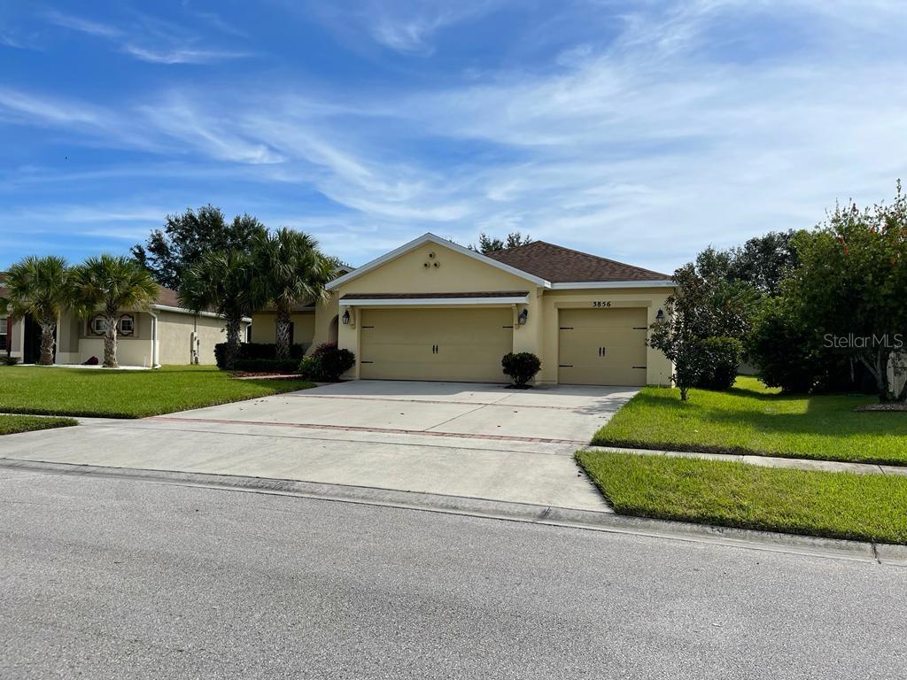 A single-story house with a beige exterior, a three-car garage, and a concrete driveway — 3856 GULF SHORE CIRCLE, KISSIMMEE, FL