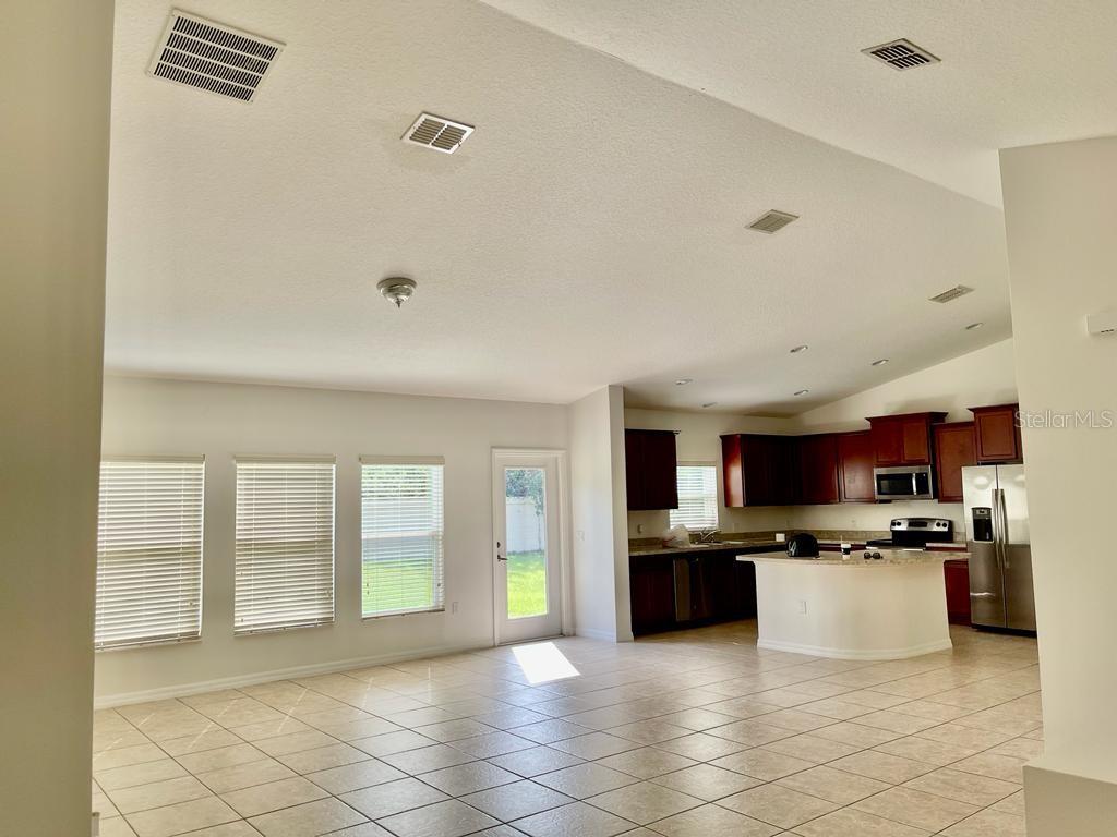 An open-concept living area with tile floors leads to a kitchen with dark wood cabinets — 3856 GULF SHORE CIRCLE, KISSIMMEE, FL