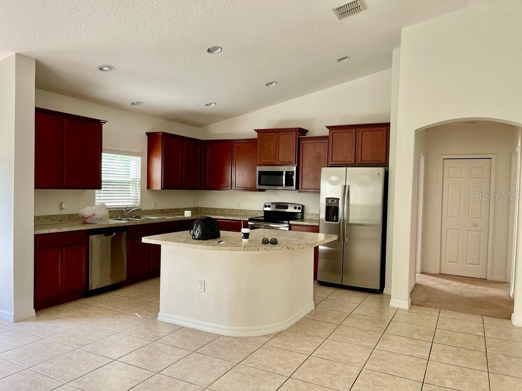 A kitchen with dark wood cabinets, stainless steel appliances, a center island, and tile flooring — 3856 GULF SHORE CIRCLE, KISSIMMEE, FL