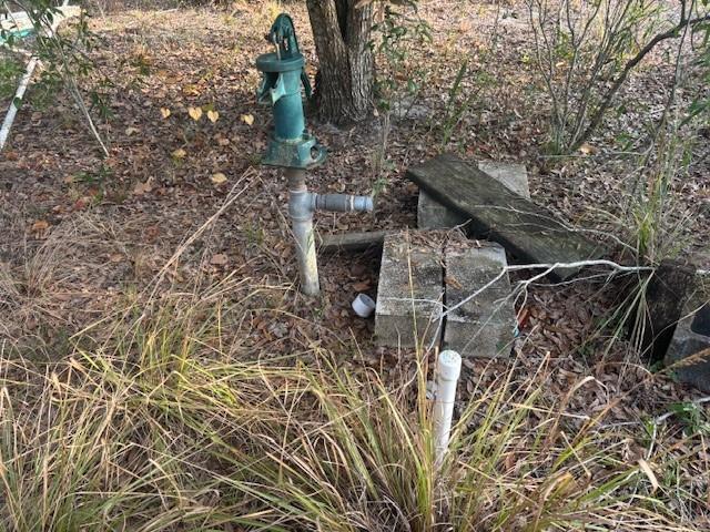 An outdoor manual water pump stands in a grassy area with concrete blocks nearby — 20745 NW 302nd Street, Okeechobee FL 34972, OKEECHOBEE, FL