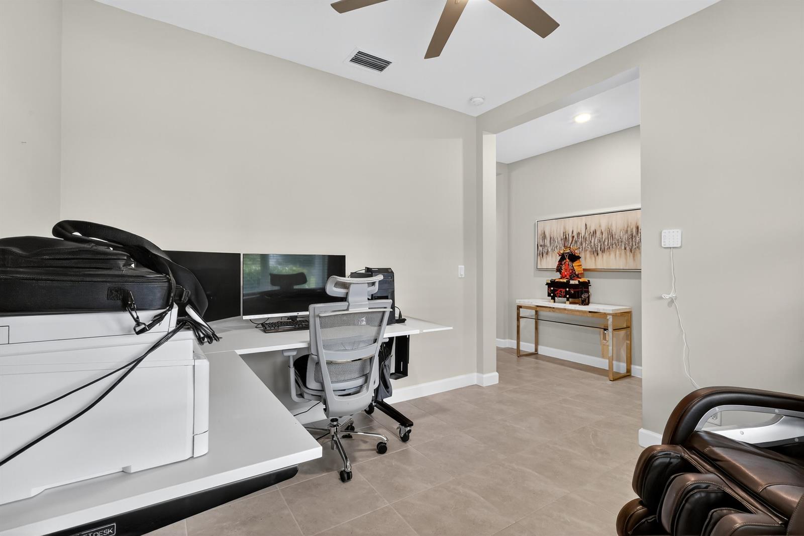 A home office features a white desk, a gray ergonomic chair, and a console table — 19753 Tree Stand Terrace, Loxahatchee FL 33470, LOXAHATCHEE, FL