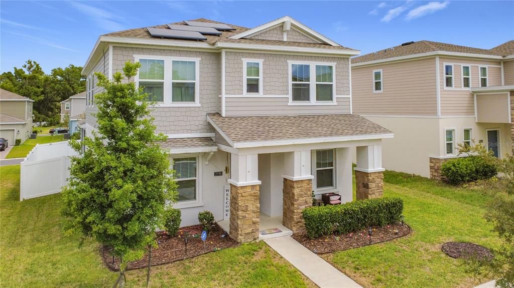 A two-story house with a stone-accented porch, shingle siding, and solar panels on the roof — 2195 SWEET HONEY LANE, APOPKA, FL