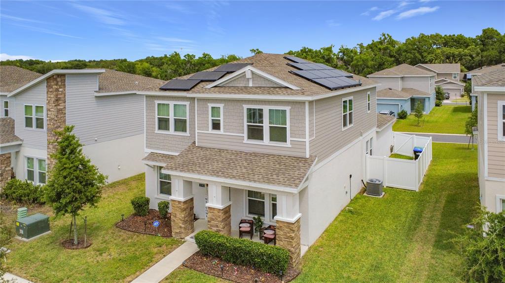 A two-story suburban house with a stone-accented porch and solar panels on the roof — 2195 SWEET HONEY LANE, APOPKA, FL