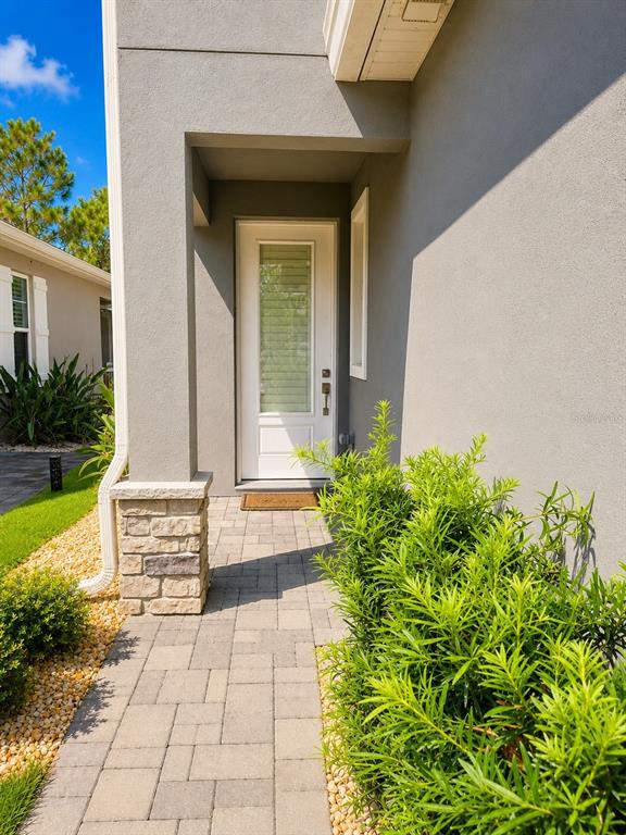 A paved walkway leads to a white front door with a stone-accented pillar — 3062 ISLES WAY, NEW SMYRNA BEACH, FL