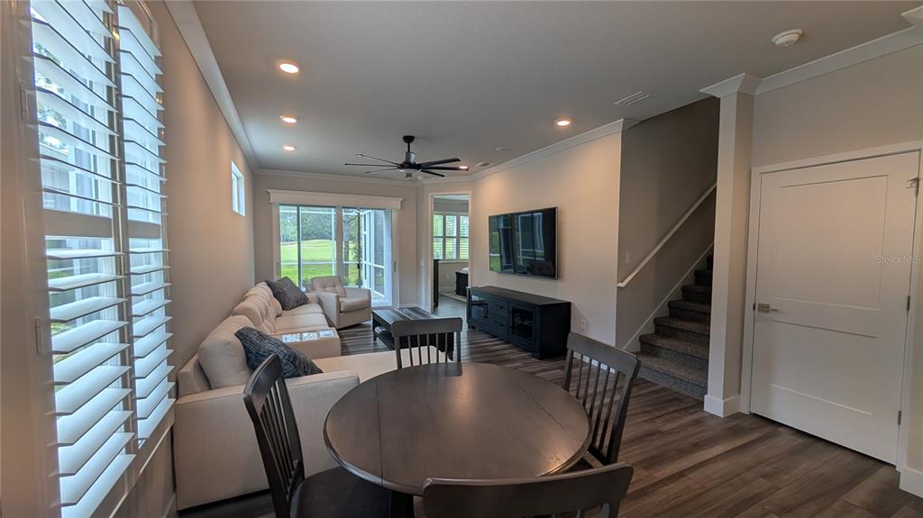 A living room and dining area feature light walls, wood-look flooring, and a staircase — 3062 ISLES WAY, NEW SMYRNA BEACH, FL