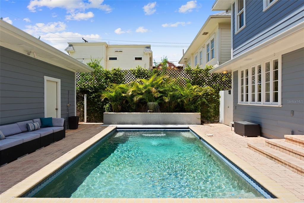 A rectangular swimming pool sits in a paved courtyard between two gray-sided buildings — 703 S EDISON AVENUE, TAMPA, FL