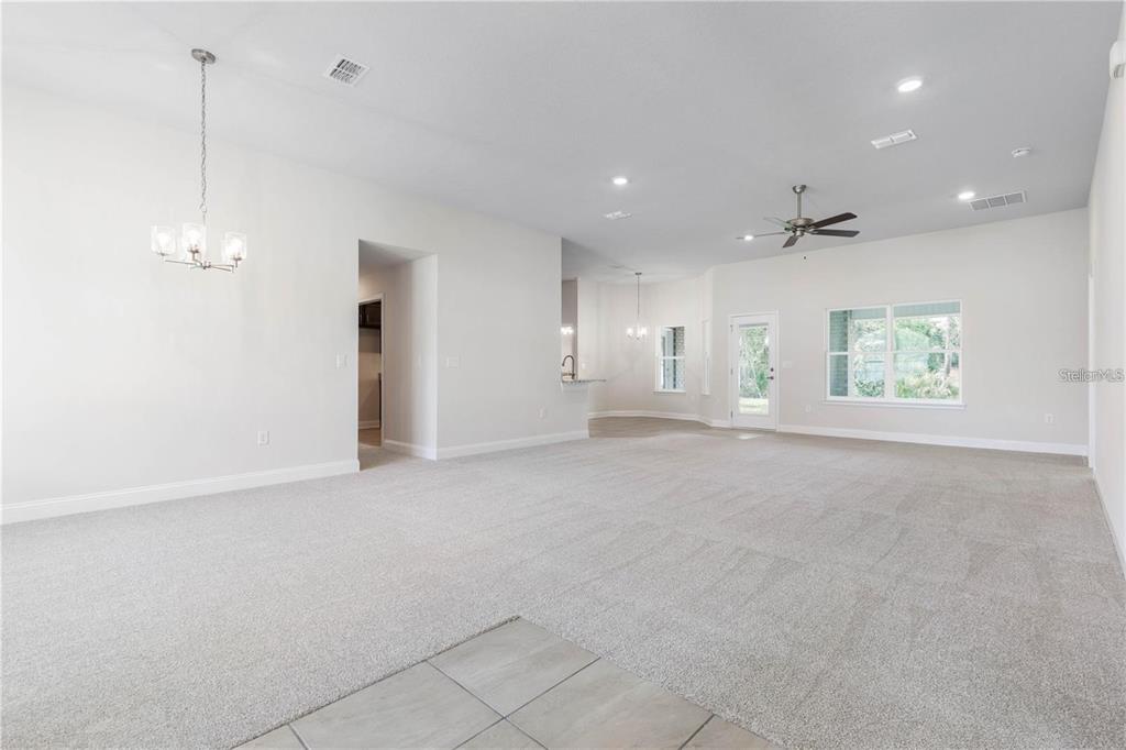 A spacious living room with neutral carpet, white walls, a ceiling fan, and recessed lighting — 74 PRINCETON LANE, PALM COAST, FL
