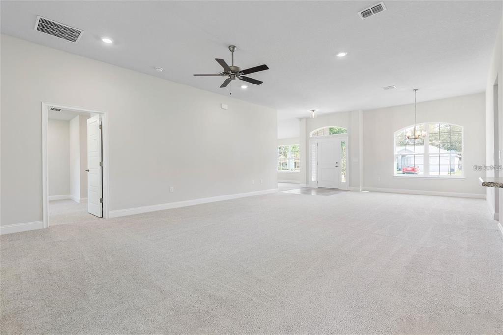 A spacious, carpeted living area features a ceiling fan, recessed lighting, and an arched entryway — 74 PRINCETON LANE, PALM COAST, FL