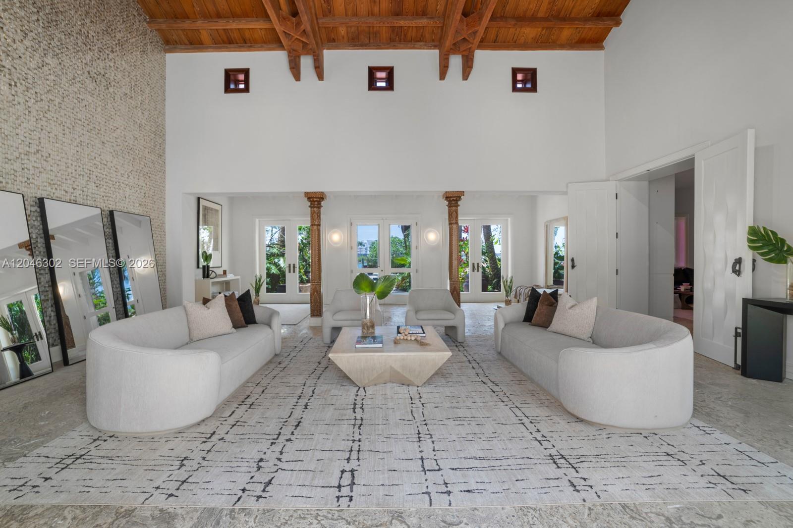 A spacious living room features a high wood-beamed ceiling, white sofas, and large floor mirrors — 16 Palm Ave, Miami Beach FL 33139, MIAMI BEACH, FL