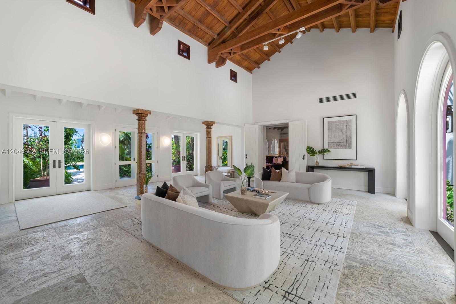 A spacious living room features a vaulted wood-beam ceiling, stone flooring, and arched doorways — 16 Palm Ave, Miami Beach FL 33139, MIAMI BEACH, FL