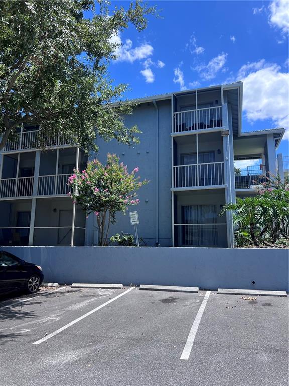 A three-story apartment building with screened balconies sits behind a paved parking lot — 126 BLUE POINT WAY UNIT 100, ALTAMONTE SPRINGS, FL