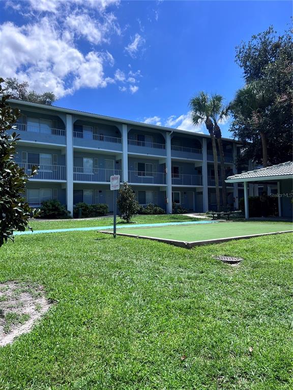 A three-story apartment building features blue siding, white balconies, and a green lawn with landscaping — 126 BLUE POINT WAY UNIT 100, ALTAMONTE SPRINGS, FL