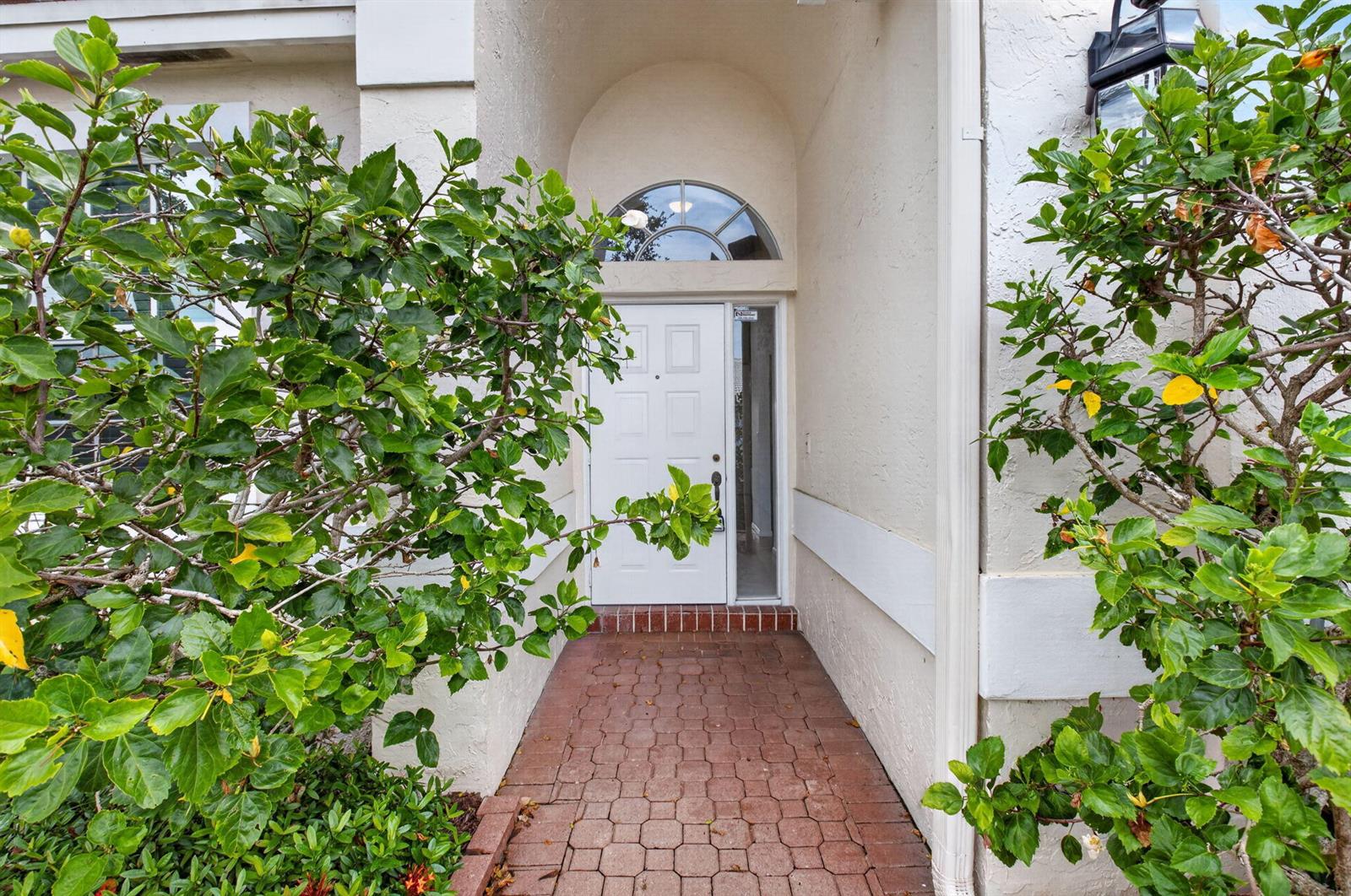 A white front door with a sidelight and arched window sits at the end of a walkway — 23256 Alora Drive, Boca Raton FL 33433, BOCA RATON, FL
