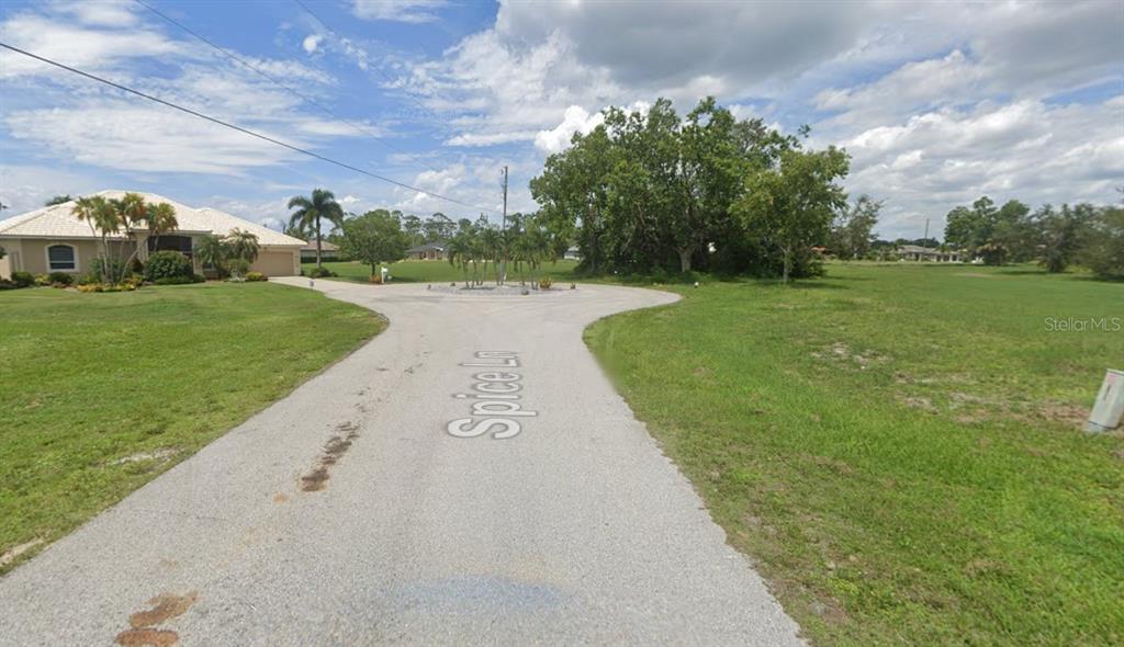 A paved road leads to a circular turnaround in a grassy residential area with trees — 17166 SPICE LANE, PUNTA GORDA, FL