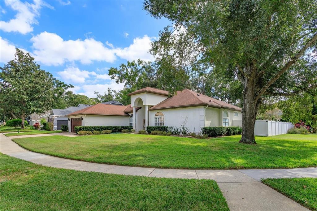 A single-story house with a white stucco exterior, brown roof, and a large front lawn — 5083 GREAT OAK LANE, SANFORD, FL