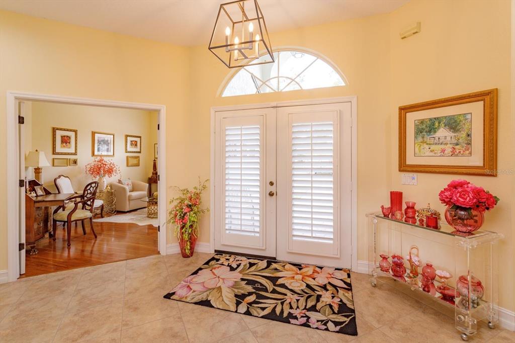 An entryway features tile flooring, a floral rug, double doors with shutters, and a chandelier — 5083 GREAT OAK LANE, SANFORD, FL