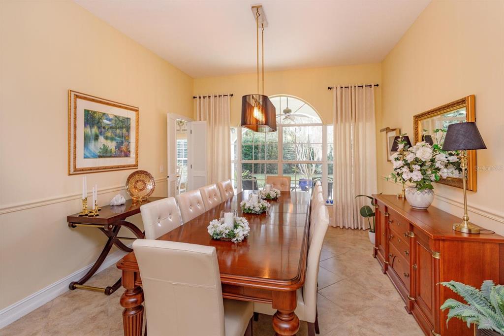A formal dining room features a long wooden table, upholstered chairs, and a side buffet — 5083 GREAT OAK LANE, SANFORD, FL