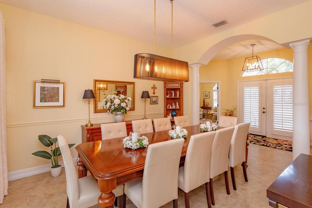 A formal dining room features a wooden table, cream chairs, and a modern rectangular pendant light — 5083 GREAT OAK LANE, SANFORD, FL