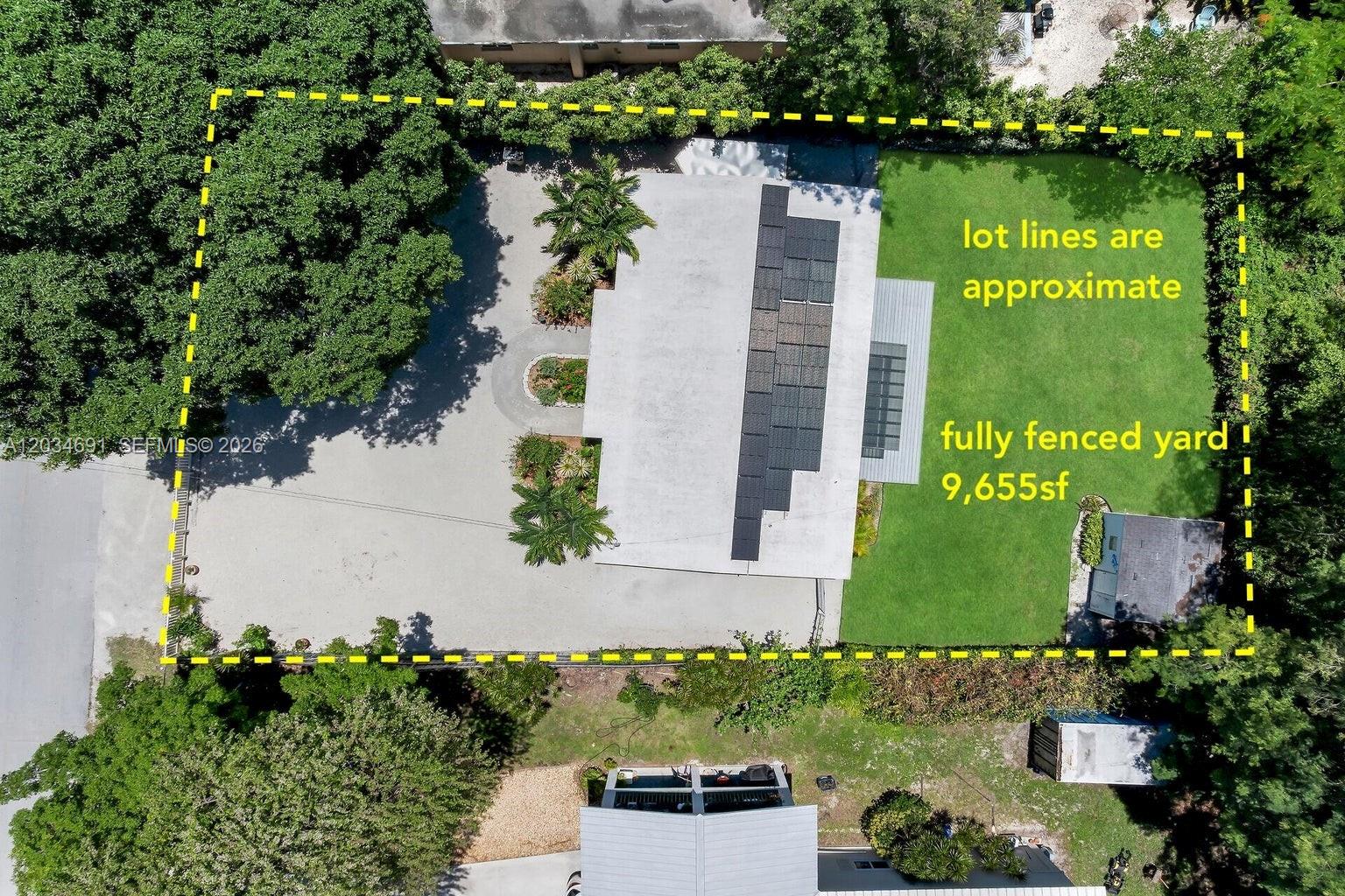 An aerial view shows a house with solar panels, a driveway, and a fenced yard — KEY LARGO, FL