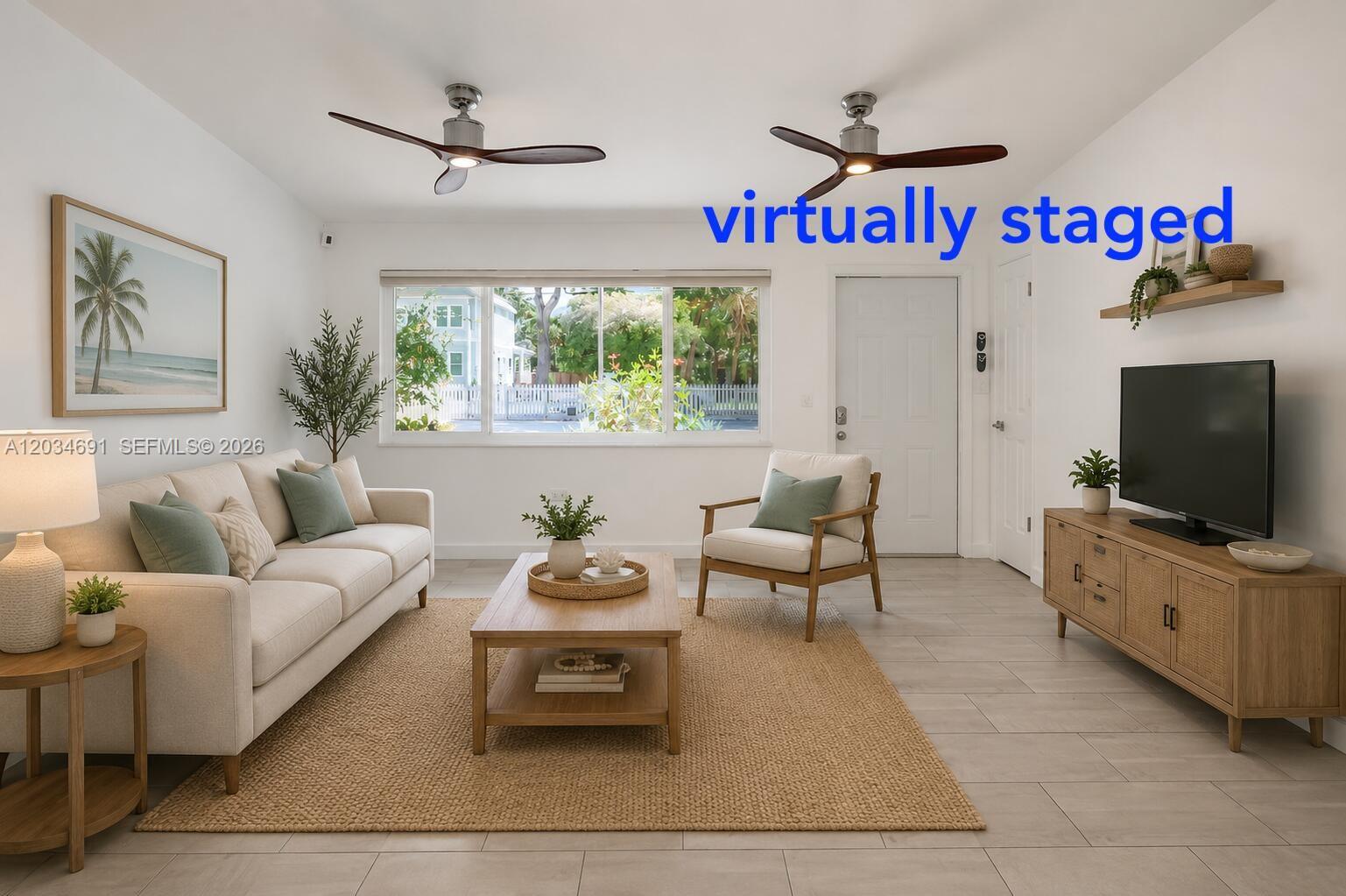 This virtually staged living room features a sofa, armchair, media console, and large window — KEY LARGO, FL