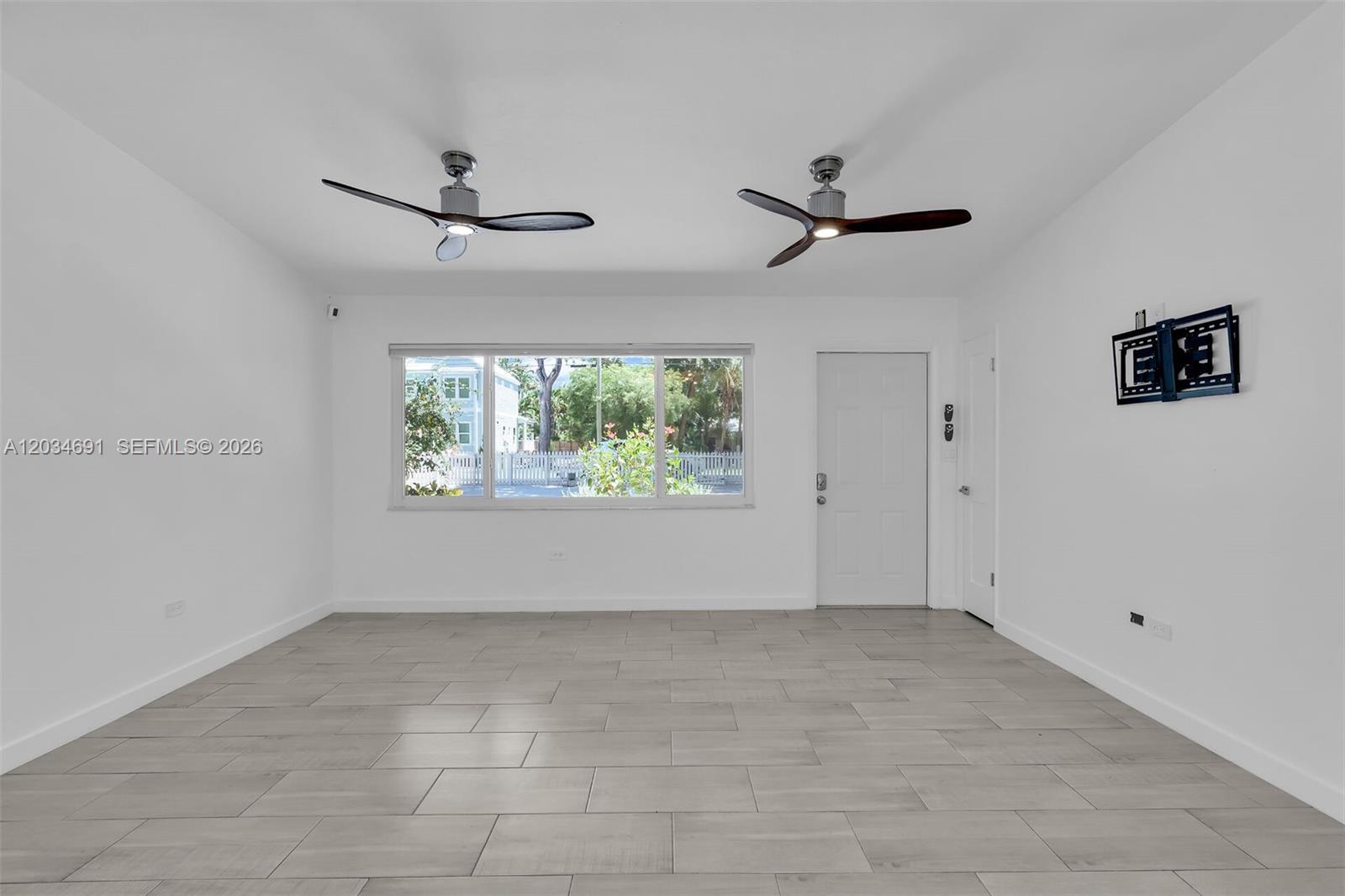 A bright, empty room features white walls, light-colored tile flooring, and two ceiling fans — KEY LARGO, FL