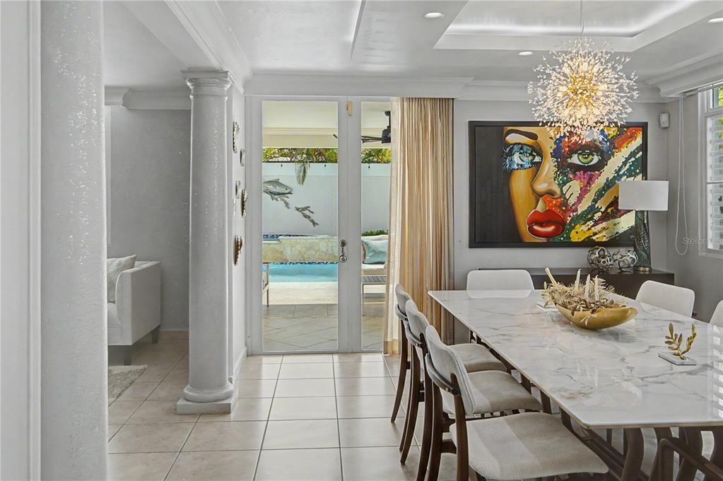 A dining room with a marble table, modern chandelier, and glass doors leading to a pool — B11 CALLE MAR CARIBE, DORADO, PR