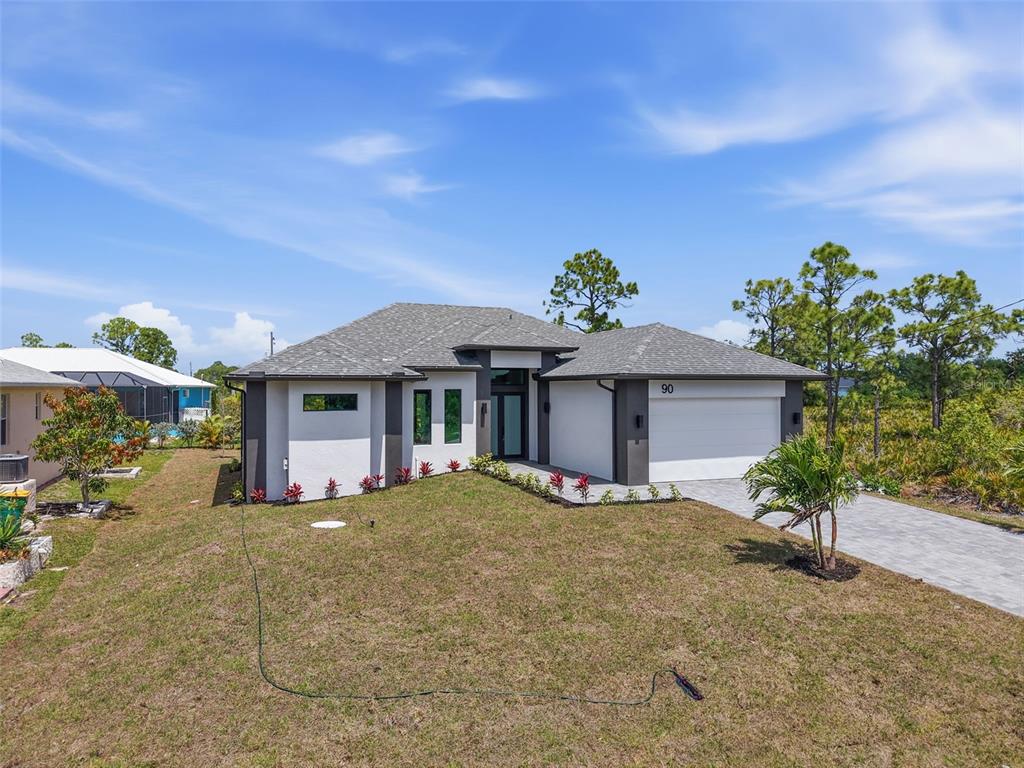 A modern single-story house with a gray roof, white stucco walls, and a two-car garage — 90 BRIG CIRCLE S, PLACIDA, FL